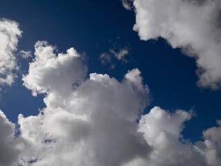 Obraz premium White cumulus clouds in the deep blue summer sky. Fluffy clouds background