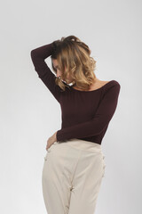 Serie of studio photos of young female model wearing comfortable basic smart casual outfit, burgundy viscose boat neckline shirt and beige trousers	