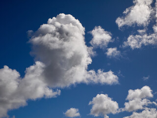 White cumulus clouds in the deep blue summer sky. Fluffy clouds background