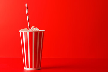 Paper cup with cola and ice over red background