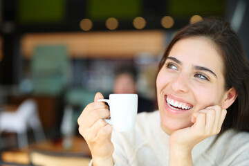 Happy woman with perfect teeth dreaming and drinking coffee