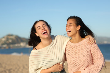 Two friends laughing hilariously on the beach - obrazy, fototapety, plakaty