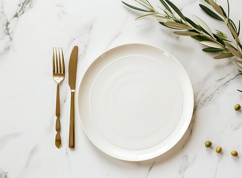 Top view of an empty plate with golden cutlery and an olive branch on a white marble table, in a flat lay top view mockup stock photo style of contest winner