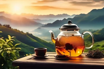 Selbstklebende Fototapeten Black tea infuser tea against a background of green tea plantations and mountains. With copy space © Margarita