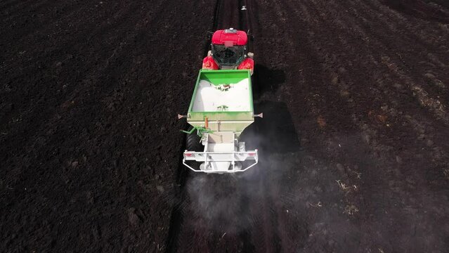 A tractor on agricultural land applies dry fertilizers to improve the yield.