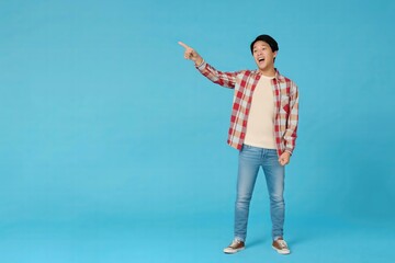 A man in a plaid shirt and blue jeans points to the sky. The image has a lighthearted and playful mood, as the man is making a joke or pointing out something interesting