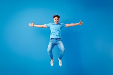Fototapeta na wymiar A man in a blue shirt and blue jeans is jumping in the air. He is smiling and he is happy
