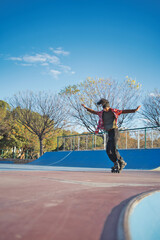 Young Latin American skateboarder dancing and doing tricks in an outdoor skate park at sunset,...