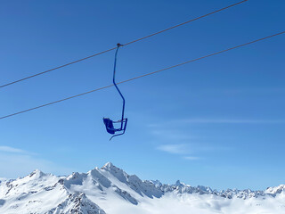 A blue seat of skiing lift in the mountains on a blue sky background