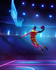 Dynamic image of young man, basketball player in motion, throwing ball into basketball hoop in a jump over neon colored arena. Sport, action, game, competition, tournament, energy concept. Poster, ad - obrazy, fototapety, plakaty