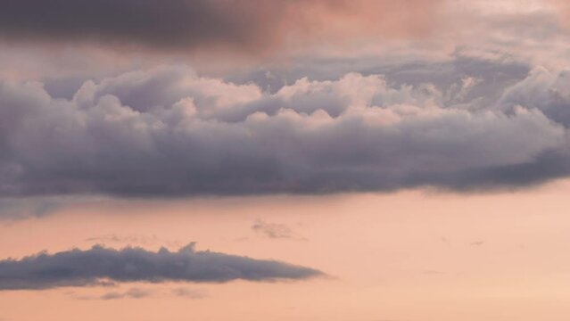 Dense clouds whirl in the sunset sky backlit by the warm glow. Timelapse video.