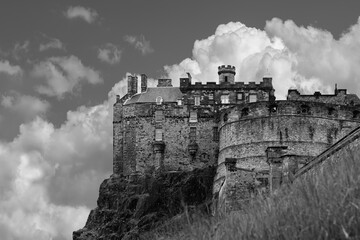 The formidable walls of Edinburgh Castle loom overhead, with cumulus clouds accentuating its...