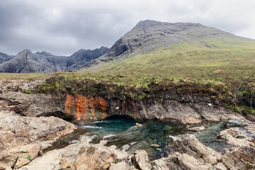 The raw beauty ofIsle of Skye unfolds where the Fairy Pools vivid waters meet ancient rocks, all...