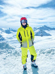 A teenager in a bright sport skiing suit in the mountains