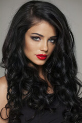 Fototapeta premium Pretty young brunette female model with long brown wavy hair and makeup closeup portrait