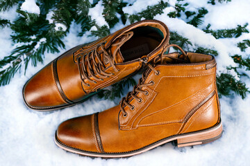 A pair of premium calfskin boots with snow background. Horizontal shot.