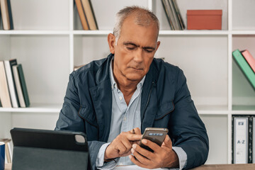 middle aged businessman using smartphone in office