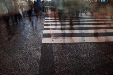 A long exposure photo of a crosswalk with blurred motion pedestrians, taken at a large intersection...