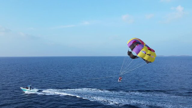 Couple on Island Vacation Parasailing at Sea, Drone View
