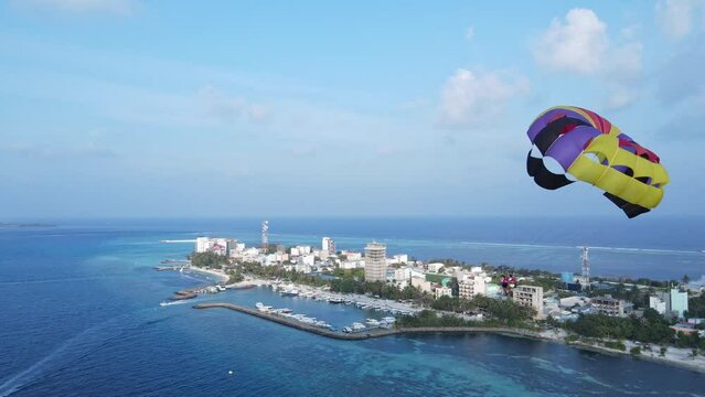 Couple on Island Vacation Parasailing High Over Sea, Drone View