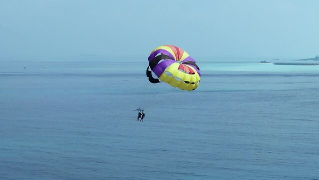 Maldives Vacationer Couple Parasailing high over sea, Drone Parallax
