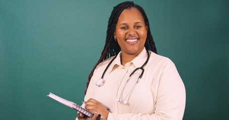 Young Black female doctor making notes on writing pad, smiling