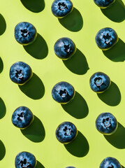 A pattern of blueberries against a bright lime green background. Summer cosmetic or food background.
