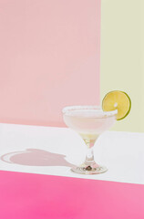 Photo of a margarita cocktail on a white and pink background, in a minimalist style with pastel colors. Summer drinks concept.