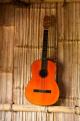 classic guitar hanging on a textured reed wall, blending art with tradition