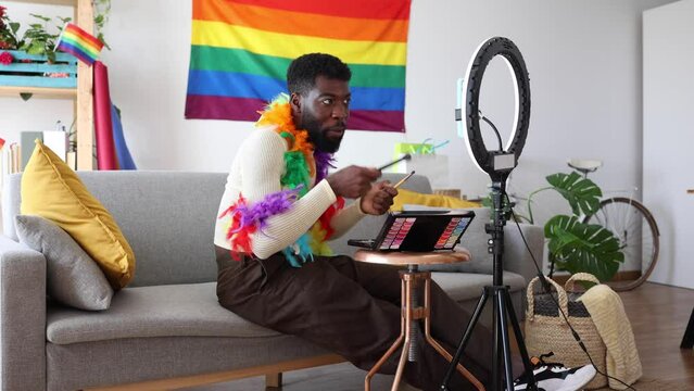 young african american man drag queen recording online streaming makeup tutorial with smartphone indoors at home - LGBT, non-binary gender
