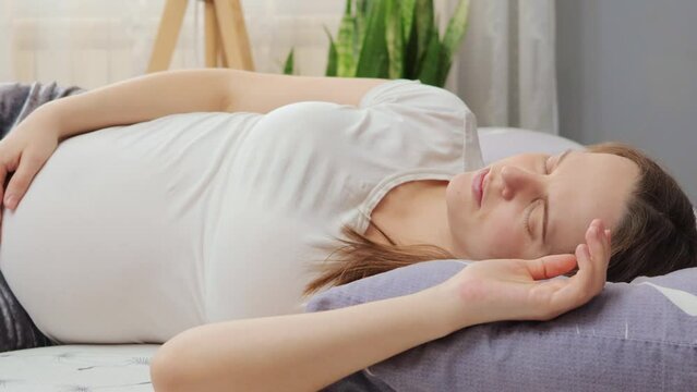Calm relaxed beautiful pregnant woman sleeping in bed at home expectant mother having daily napping resting in comfortable pose wearing white casual T-shirt
