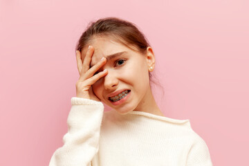 excited teenage girl is worried and shows a facepalm on a pink isolated background, an unhappy...