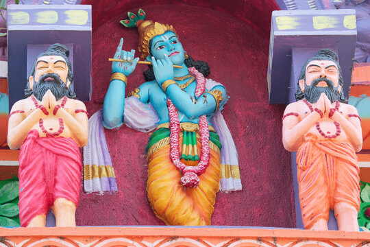Krishna with a flute and Rishi sages. A fragment of decoration on the wall of a Hindu temple in India.