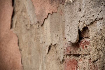 Texture of an old ragged wall. Background of old bricks and cracks in plaster. Yellow and brown tones