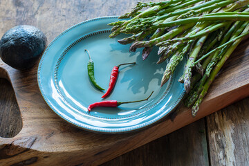 asparagus and hot colorful peppers on a blue plate on a wooden board.  photo in a dark key.fresh spring food. proper nutrition.
- 773868882