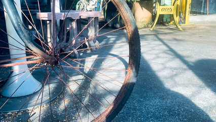 A rusty old bicycle wheel is sitting on the ground