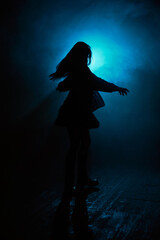 cinematic silhouette of a dancing woman with blue lights and fog in the background. 