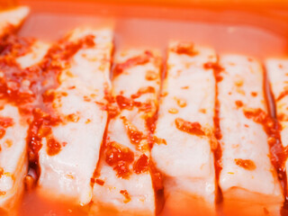 Raw pork chops in plastic container with red liquid marinade. Uncooked meat preparation. Isolated white background.
