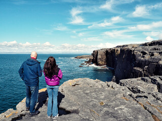 Father and daughter enjoy stunning view of mini Cliff in county Clare, Ireland. Warm sunny day....