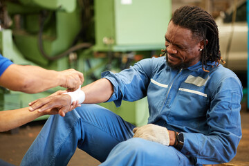 worker first aid and applying bandage on technician arm in the factory
