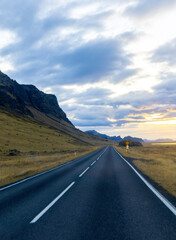 A long road with no cars on it and a mountain in the background