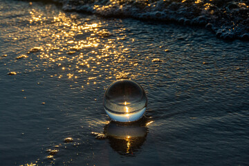 Glass ball lies in the water in the waves at the sea - 773874621