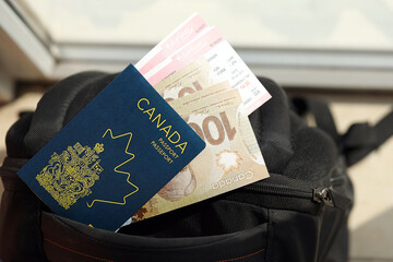 Canadian passport and dollar money bills with airline tickets on backpack close up - obrazy, fototapety, plakaty