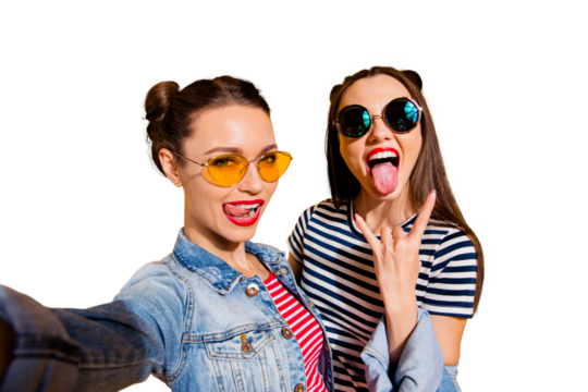 Carefree careless funny glad two girlish lady isolated on yellow shine background in trendy glasses spectacles take picture on cellular give heavy metal gesture show stick out