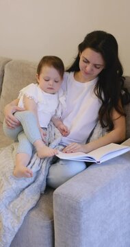 curly mother reading book to her cute little daughter. baby girl kissing her mom