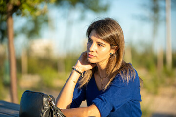 Relaxed and thoughtful woman sitting outdoors in a park.