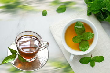 Mint tea in a glass cup on a wooden background with fresh leaves and lemon tea.