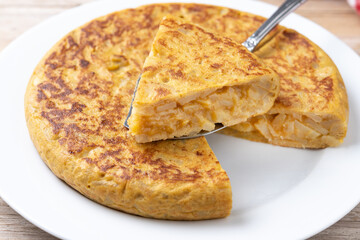 Traditional spanish omelette with ingredients on wooden table..
