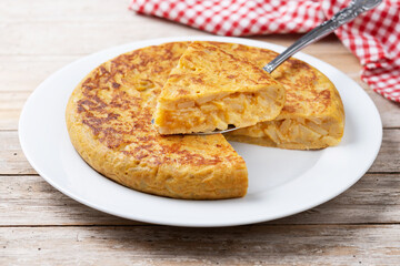 Traditional spanish omelette with ingredients on wooden table..