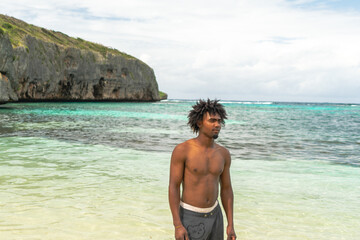 Portrait of black boy with afro hair on a beach with turquoise water. smiling boy. Paradise Beach.